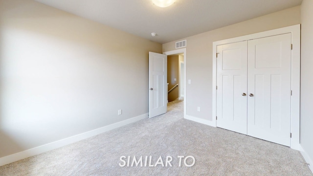 unfurnished bedroom with light carpet and a closet