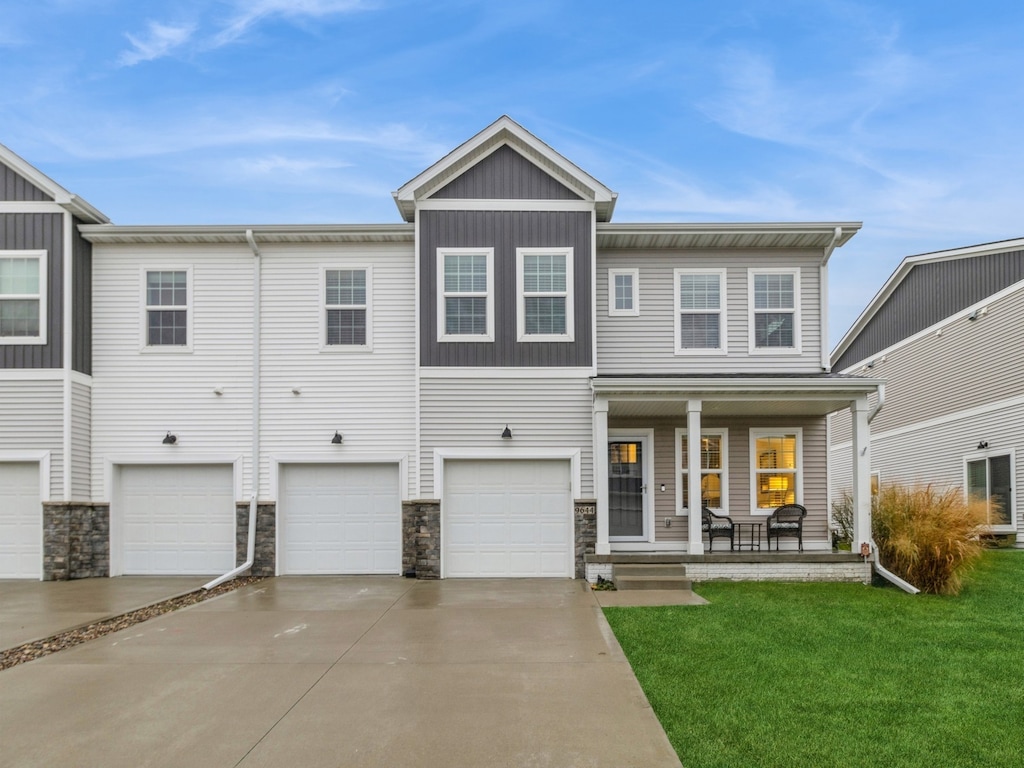 view of front of house with a garage, covered porch, and a front lawn