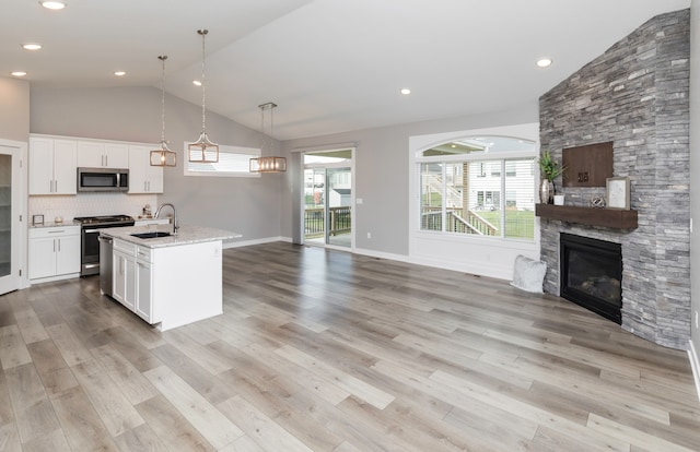 kitchen with sink, hanging light fixtures, stainless steel appliances, light hardwood / wood-style floors, and white cabinets