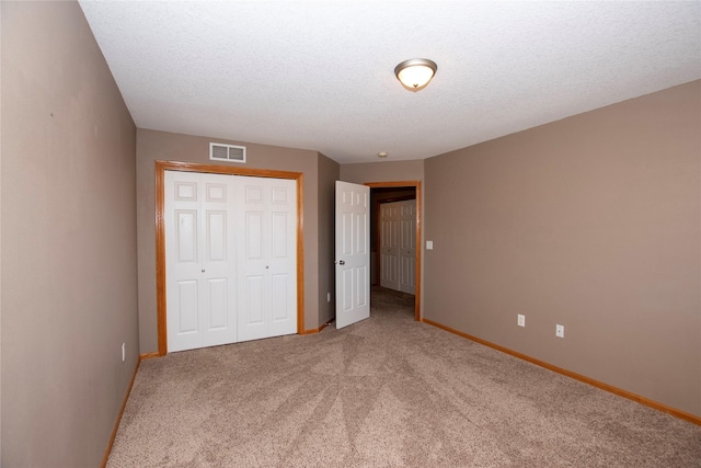 unfurnished bedroom with carpet flooring, a textured ceiling, and a closet