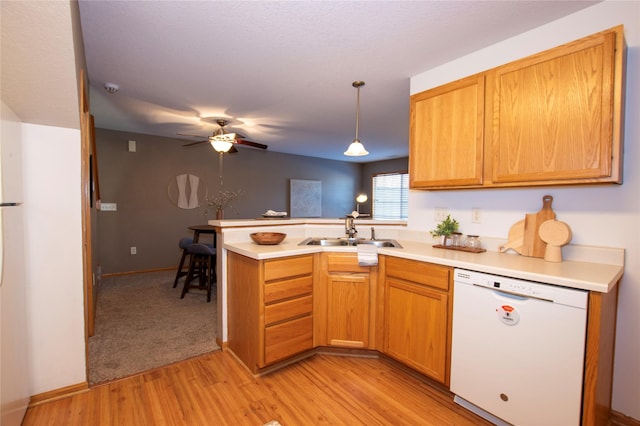 kitchen with dishwasher, sink, hanging light fixtures, light hardwood / wood-style floors, and kitchen peninsula