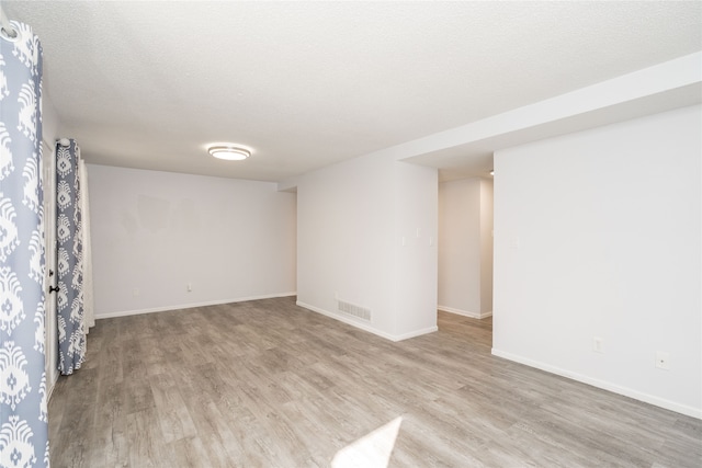 empty room featuring a textured ceiling and light hardwood / wood-style flooring