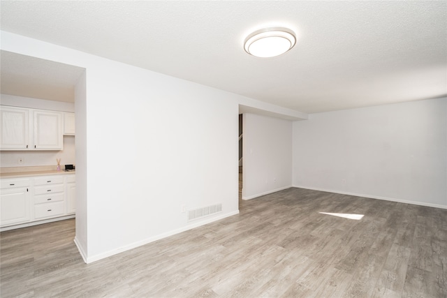 unfurnished room with light hardwood / wood-style flooring and a textured ceiling