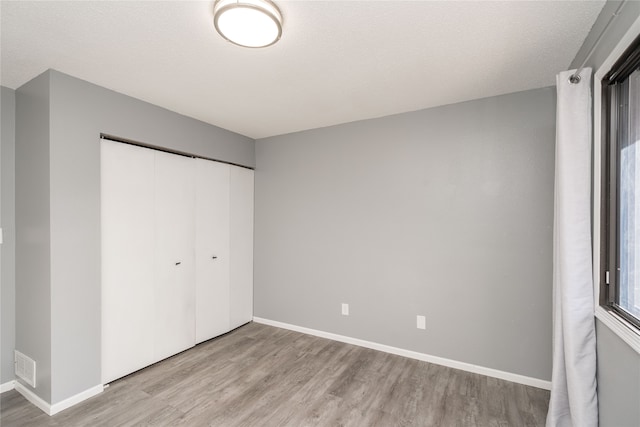 unfurnished bedroom with a textured ceiling, light hardwood / wood-style flooring, and a closet