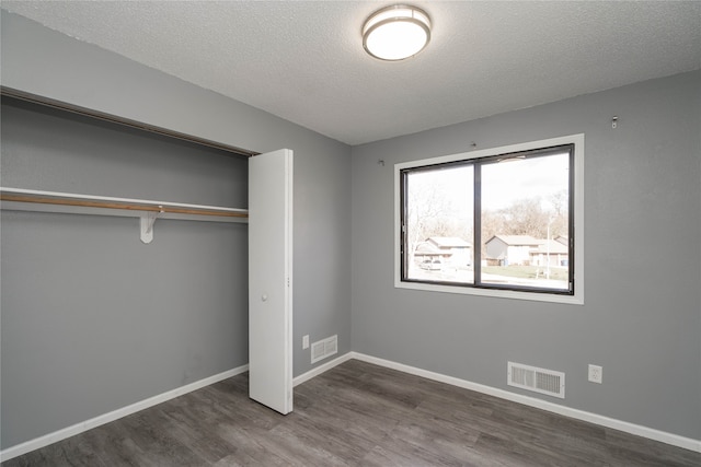 unfurnished bedroom featuring a closet, dark wood-type flooring, and a textured ceiling