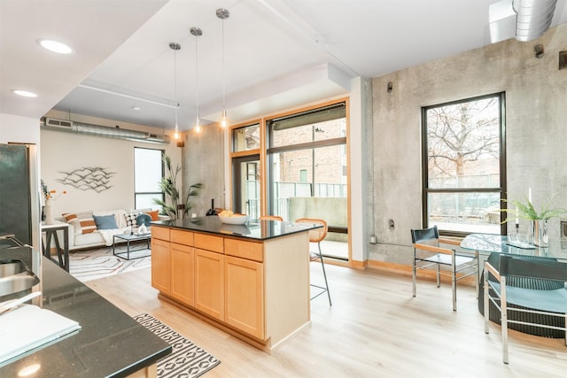 kitchen with a kitchen island, pendant lighting, stainless steel fridge, and light wood-type flooring