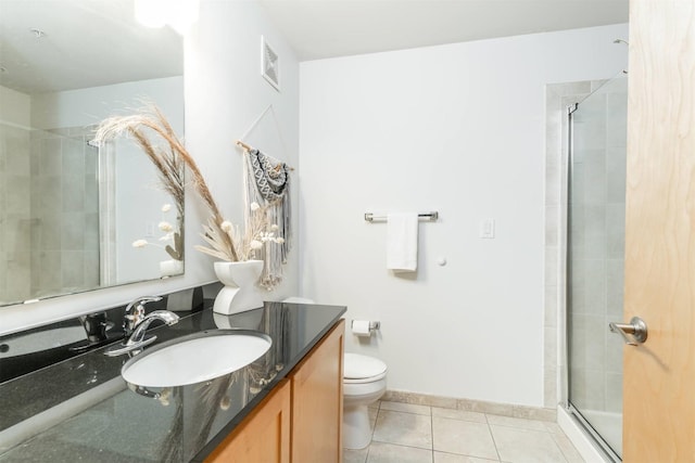 bathroom with tile patterned flooring, vanity, a shower with shower door, and toilet