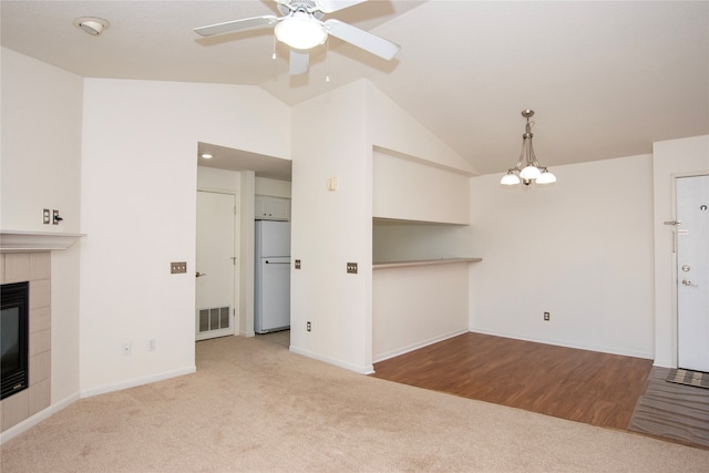 unfurnished living room featuring a fireplace, ceiling fan with notable chandelier, light colored carpet, and lofted ceiling