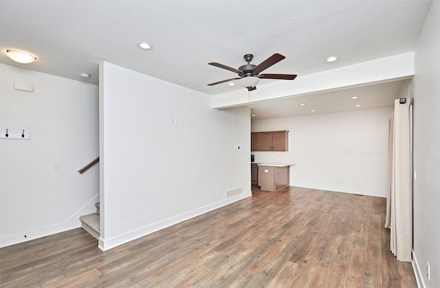 unfurnished living room featuring dark hardwood / wood-style floors, ceiling fan, and a textured ceiling