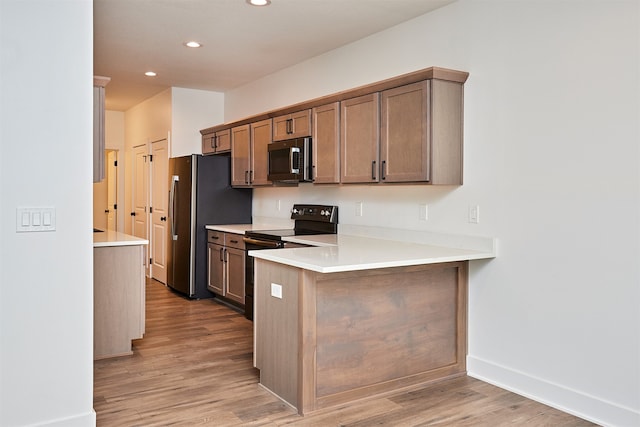 kitchen featuring kitchen peninsula, light hardwood / wood-style flooring, and stainless steel appliances