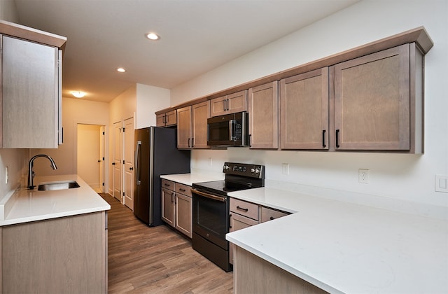 kitchen featuring dark hardwood / wood-style flooring, sink, stainless steel refrigerator, and black / electric stove