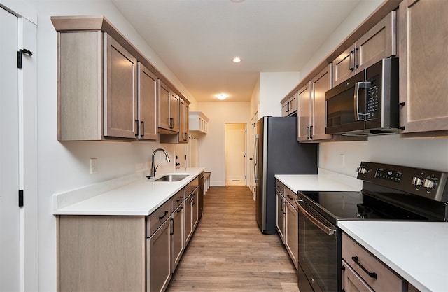 kitchen with electric range, light hardwood / wood-style floors, and sink