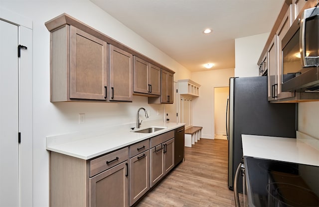 kitchen featuring dishwasher, light hardwood / wood-style floors, stove, and sink