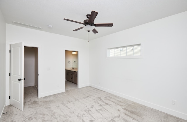 unfurnished bedroom with ceiling fan, light carpet, and connected bathroom