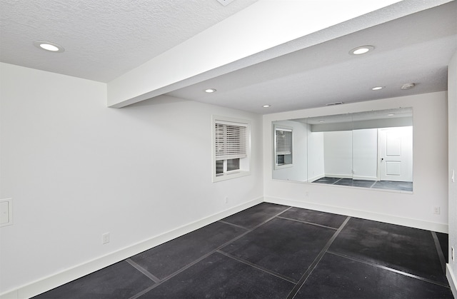 tiled empty room featuring a textured ceiling