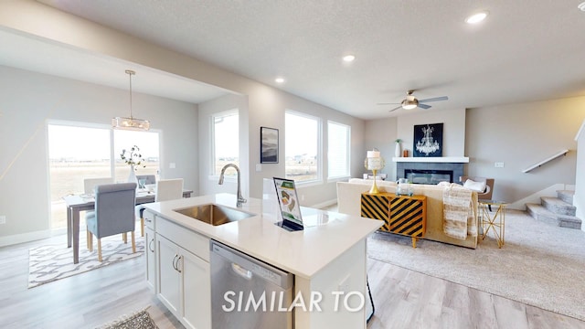 16409 Deerview Dr, Urbandale, IA 50323 - kitchen featuring ceiling fan, a sink, a glass covered fireplace, light wood-style flooring, and stainless steel dishwasher