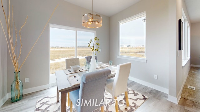 dining room with light hardwood / wood-style floors and an inviting chandelier