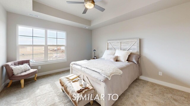 carpeted bedroom with a tray ceiling and ceiling fan