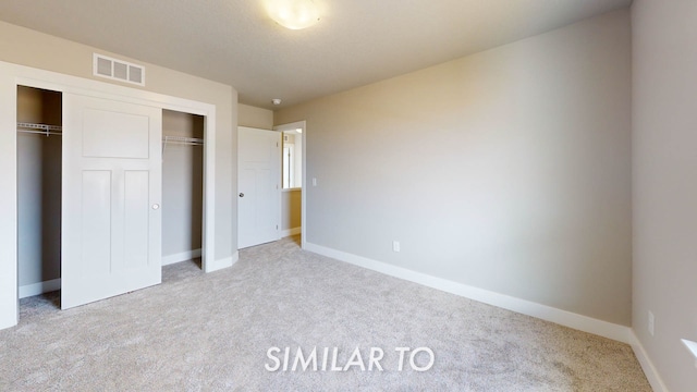 unfurnished bedroom with light carpet and a closet