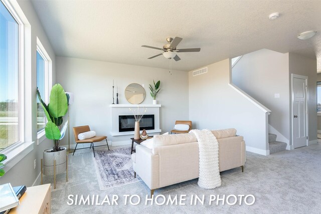 carpeted living room with a textured ceiling and ceiling fan