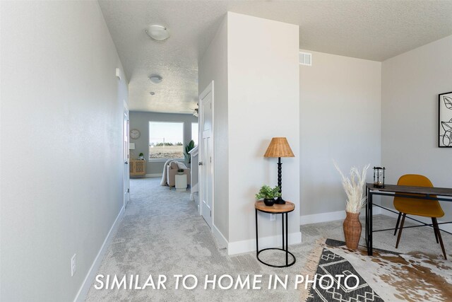 hall with light carpet and a textured ceiling