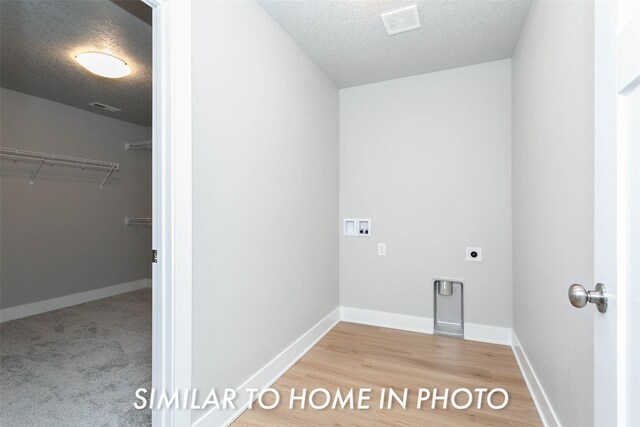 laundry room featuring wood-type flooring, hookup for an electric dryer, washer hookup, and a textured ceiling