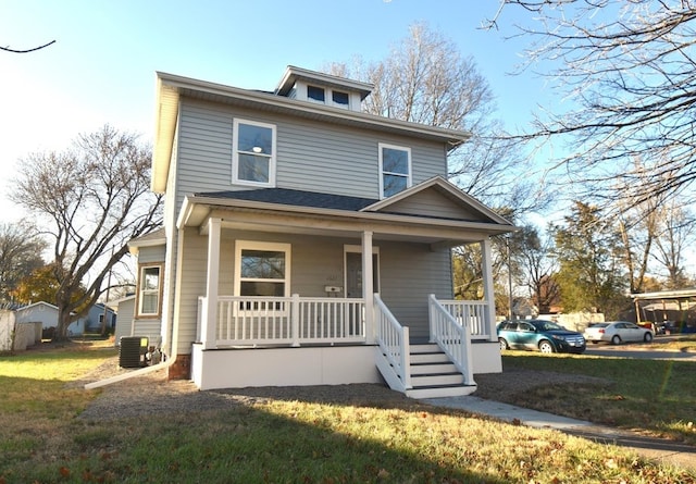 view of front facade with covered porch, central AC unit, and a front yard