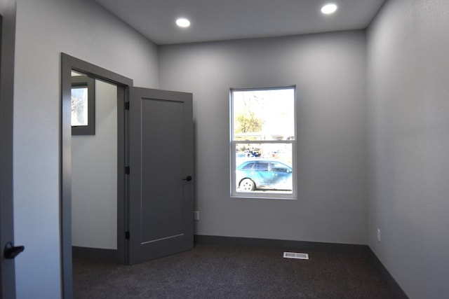 unfurnished room featuring dark colored carpet