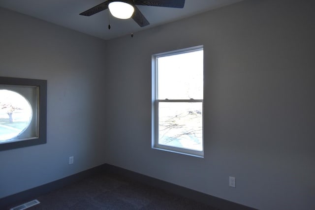 spare room featuring ceiling fan and dark colored carpet