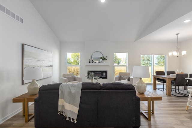 living room featuring vaulted ceiling, a chandelier, and hardwood / wood-style flooring