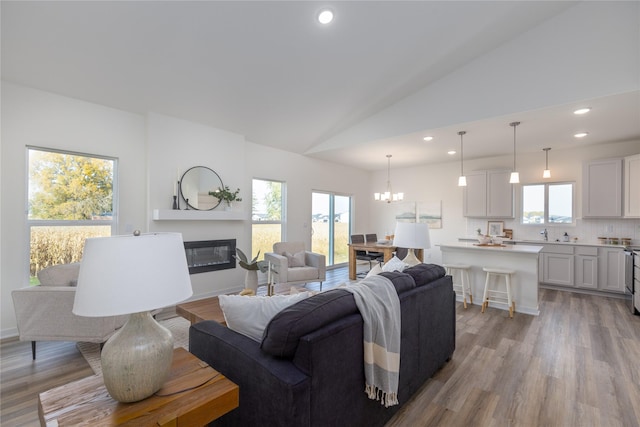 living room featuring high vaulted ceiling, a chandelier, and light hardwood / wood-style floors