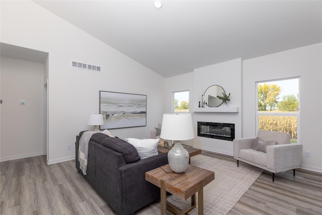 living room featuring high vaulted ceiling, light hardwood / wood-style flooring, and plenty of natural light