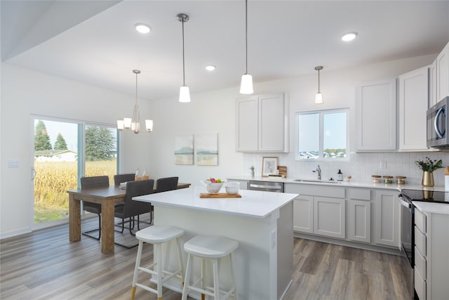 kitchen featuring appliances with stainless steel finishes, pendant lighting, white cabinetry, and wood-type flooring