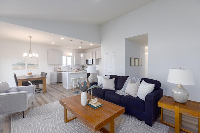 living room featuring an inviting chandelier, vaulted ceiling, and light hardwood / wood-style flooring