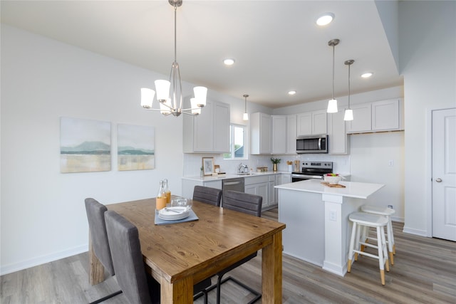 dining space with an inviting chandelier, light wood-type flooring, and sink