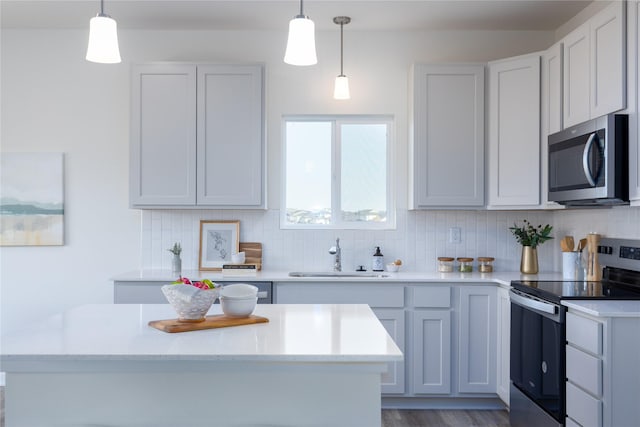 kitchen with sink, decorative backsplash, pendant lighting, and appliances with stainless steel finishes