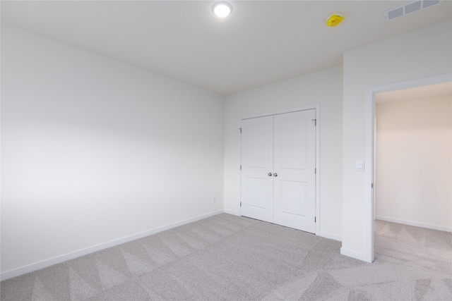 unfurnished bedroom with a closet and light colored carpet