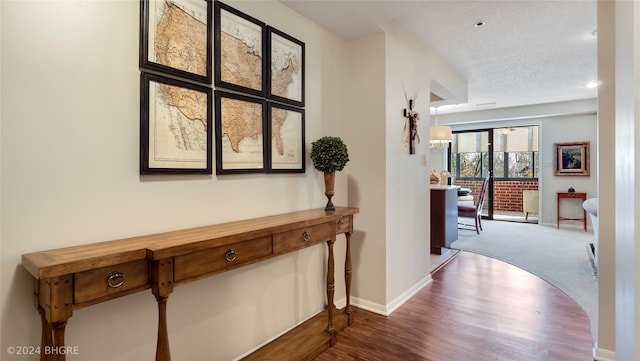 hall with wood-type flooring and a textured ceiling