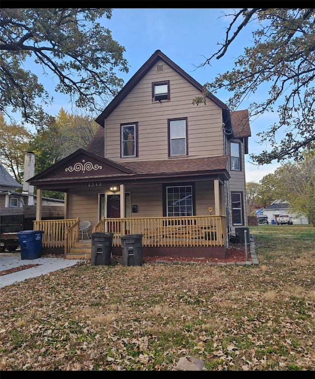 view of front of home featuring central AC unit, a porch, and a front yard