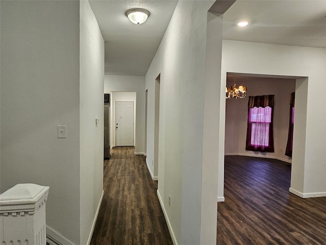 hall with dark wood-type flooring and a notable chandelier