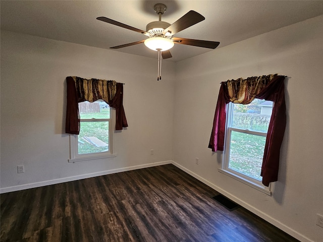 empty room with plenty of natural light, dark hardwood / wood-style floors, and ceiling fan