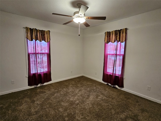 empty room featuring dark colored carpet, ceiling fan, and a healthy amount of sunlight