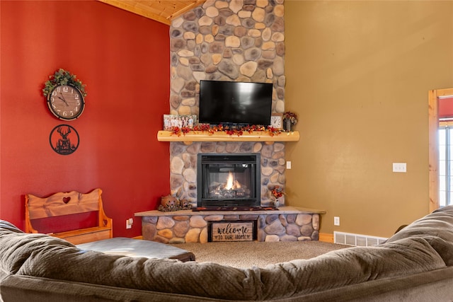 living room with a stone fireplace and vaulted ceiling