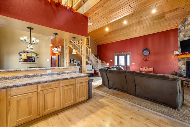 kitchen featuring light wood-type flooring, decorative light fixtures, high vaulted ceiling, wooden ceiling, and a stone fireplace