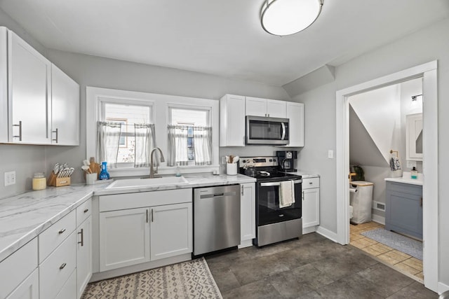 kitchen featuring light stone counters, stainless steel appliances, sink, white cabinetry, and lofted ceiling