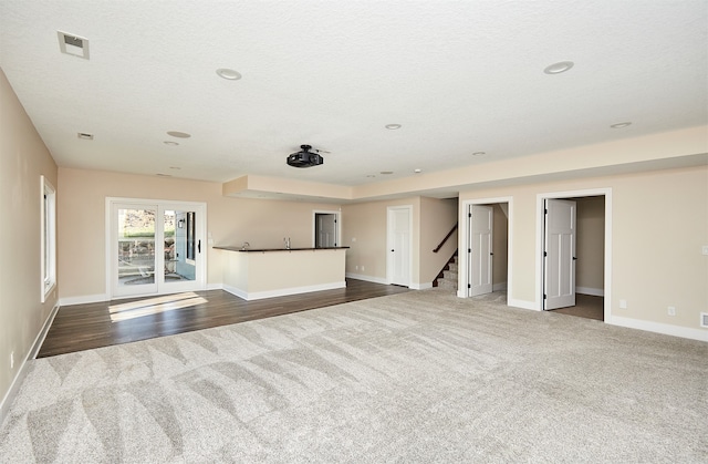 unfurnished living room with a textured ceiling and dark hardwood / wood-style flooring