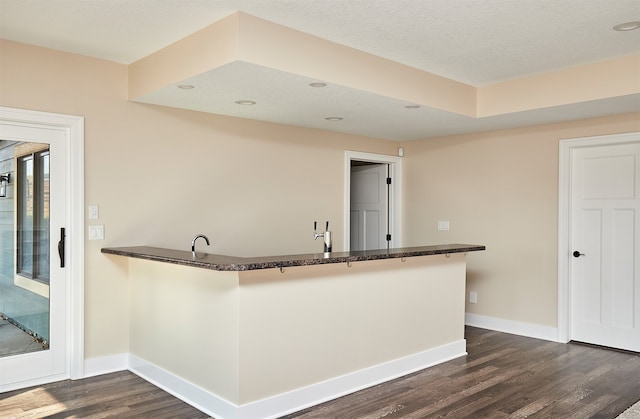 kitchen with kitchen peninsula, a textured ceiling, and dark hardwood / wood-style flooring