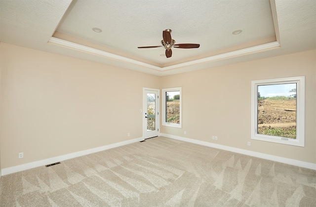 carpeted spare room featuring ceiling fan, a textured ceiling, and a tray ceiling