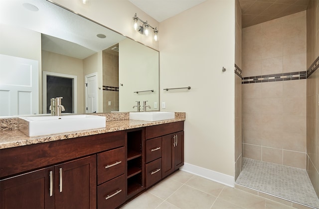 bathroom with tile patterned flooring, vanity, and tiled shower