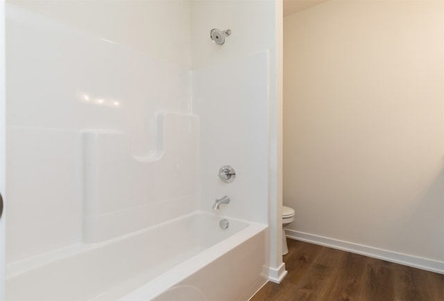 bathroom with washtub / shower combination, wood-type flooring, and toilet